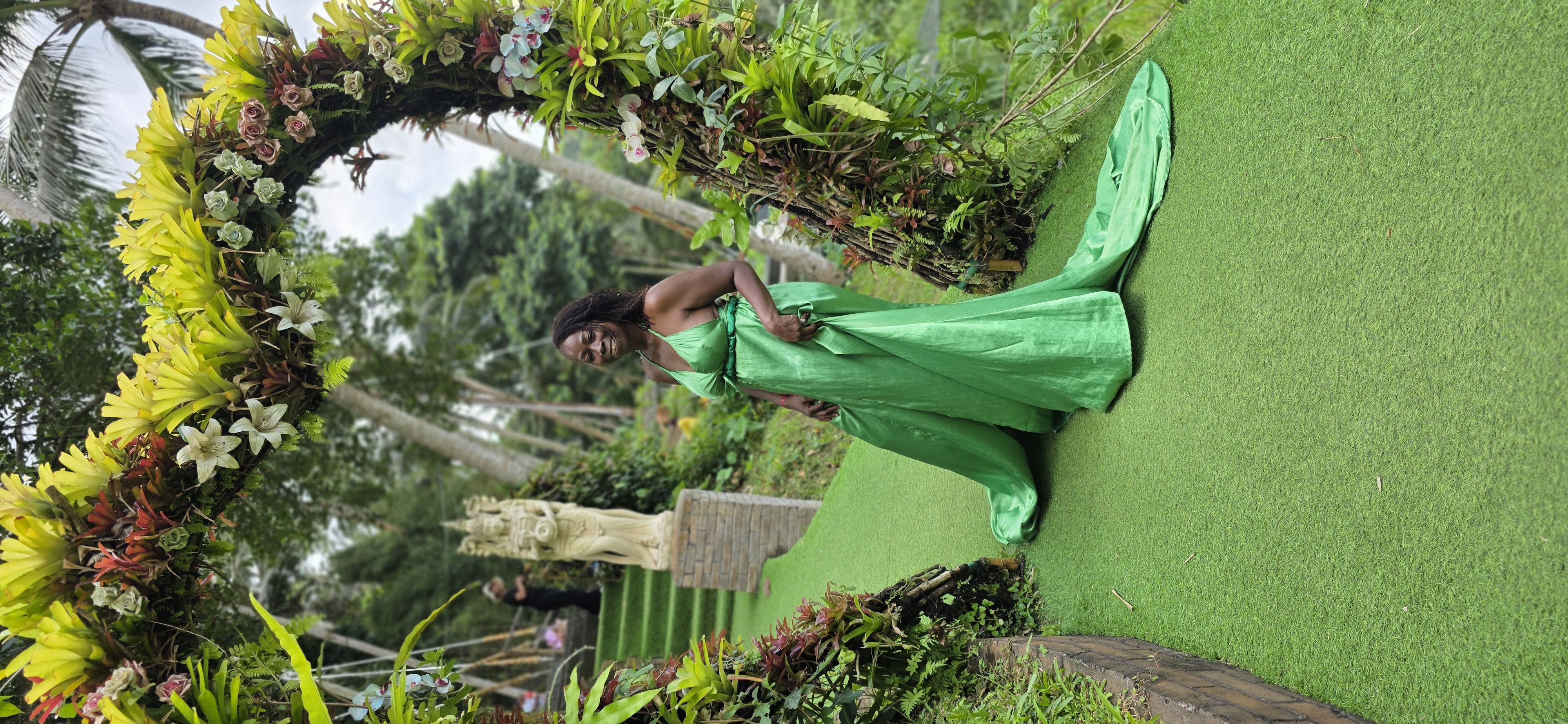 Traveler in a green gown on a Bali garden pathway